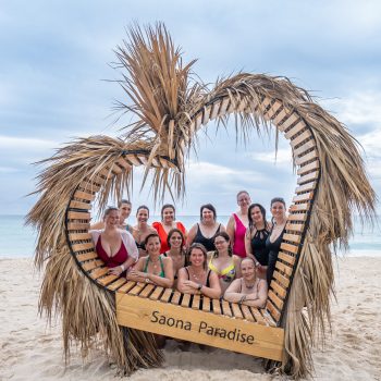 Tourists posing inside a palm heart frame marked “Saona Paradise”