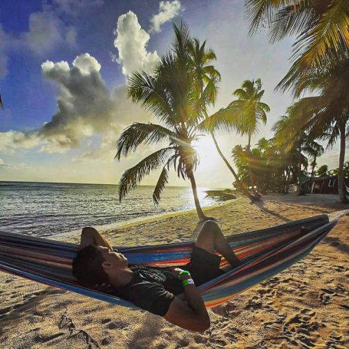 Femme sur un hamac au coucher de soleil sur la plage face a la mer et cocotiers
