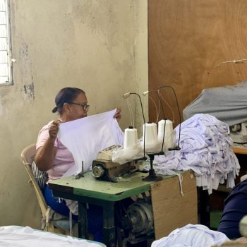 Local woman folding handmade clothes inside a community factory