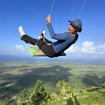 Man swinging high above the hills of Montaña Redonda with panoramic views