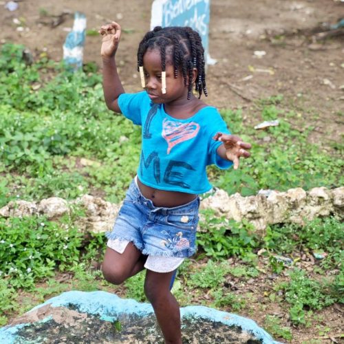 Petite fille du village de coupeurs de canne à sucre dansant sur un rocher