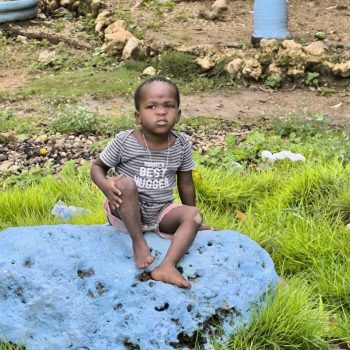 Petit garcon regardant les toursites assis sur une pierre du village