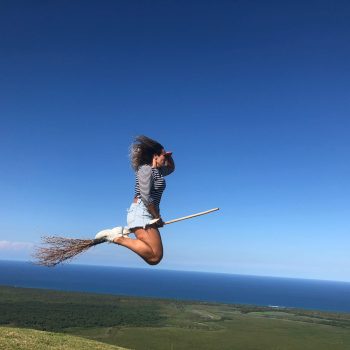 Tourist jumping mid-air with a broom in a playful witch-themed photo at Montaña Redonda