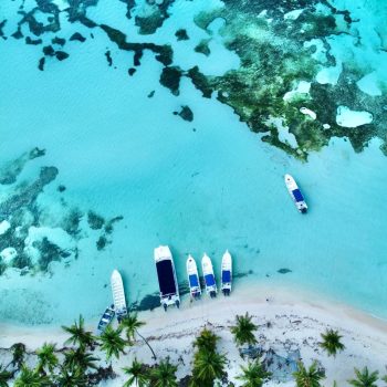 Crystal-clear turquoise lagoon with boats anchored near Saona Island