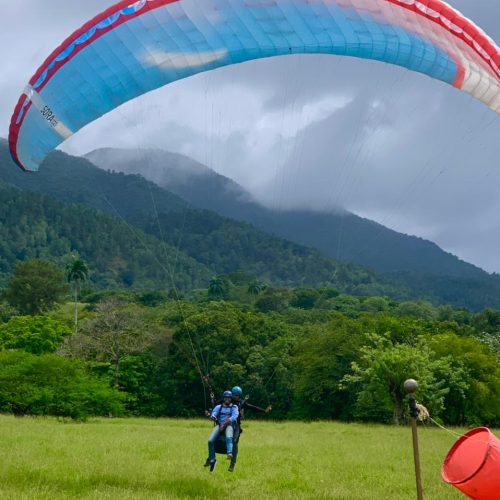 Atterrissage parapente dans un champs verdoyant et paysage montagneux